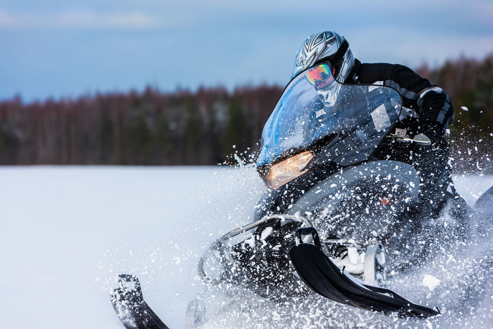 Person riding a snowmobile through deep snow